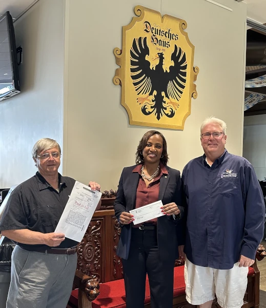 Deutsches Haus President and GM make the final mortgage payment and are presented with a Paid in Full Mortgage.